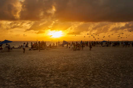 Silouette of people watching the sunset on the sea in the beach of Isla Mujeres in Mexicoの写真素材