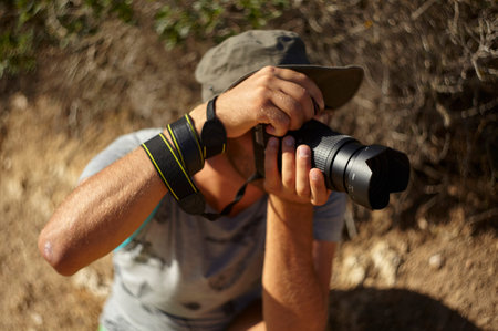 Nature photographer in action with his reflex while he is shooting a reportage service surrounded by...