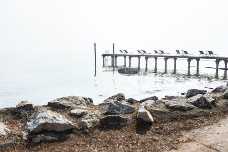 A serene and atmospheric scene of a misty pier stretching out into a calm lake, evoking feelings of peaceful solitudeの写真素材