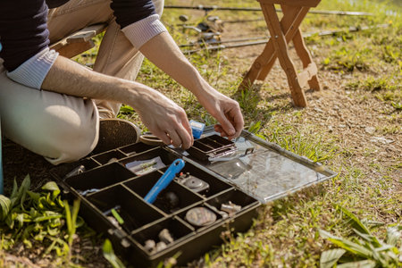 A photo of a fisherman getting ready to catch carp, preparing bait on the riverbank.