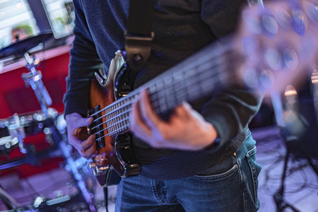 Close-up detail of a bassist's hand playing the frets of a bass guitar during a live performance.の写真素材