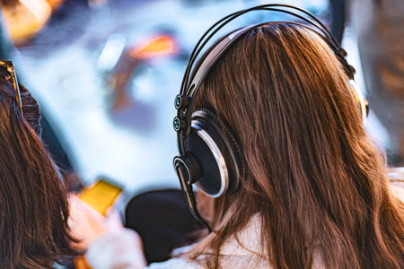 A young woman captured from behind wearing studio headphones in a professional setting.