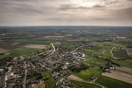 Captivating aerial perspective of a quaint village nestled amidst the lush, green Po Valley farmlands in Italyの写真素材