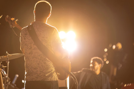 Fratta Polesine, Italy 10 December 2023: A guitarist's silhouette stands out in a night concert with a captivating backlight and fog effect.のeditorial素材
