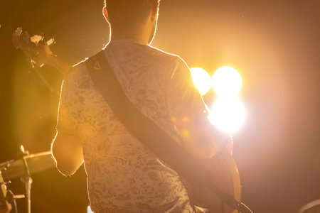 Fratta Polesine, Italy 10 December 2023: A guitarist's silhouette stands out in a night concert with a captivating backlight and fog effect.のeditorial素材