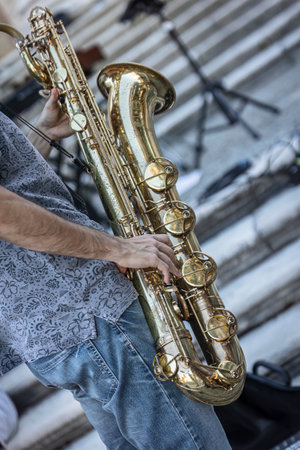 Close-up of a musician's hands playing the trumpet during a vibrant live performance in daylight.の写真素材