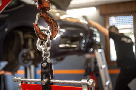 Close-up of an engine being hoisted by a chain in a workshop, pointing to auto repair service.