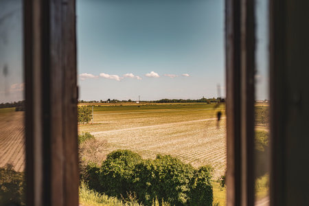 Scenic view of the Po Valley countryside during summer seen through a window, showing expansive fields under a clear sky.の写真素材