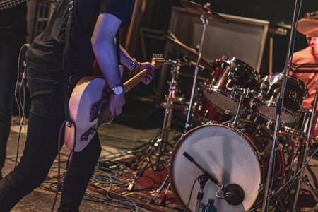 Milan, Italy 12 June 2024: A close-up shot of a musician playing a Squier electric guitar, wearing a Rolling Stones t-shirt. The scene is set on stage with vibrant lighting highlighting the performance.のeditorial素材