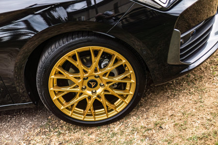 Gavello, Italy 23 June 2024: A close-up shot of a Cupra car showing its striking gold alloy wheel. The car's glossy black exterior contrasts sharply with the gold wheelのeditorial素材