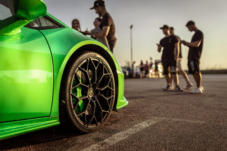 Adria, Italy 30 July 2024: Close-up shot of a green Lamborghini wheel with people in the background...