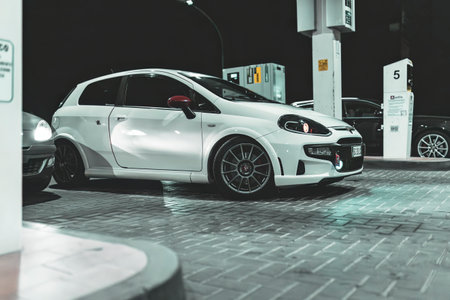 Adria, Italy 30 July 2024: White Fiat Punto Abarth parked at a gas station at night with custom wheels and sporty designのeditorial素材