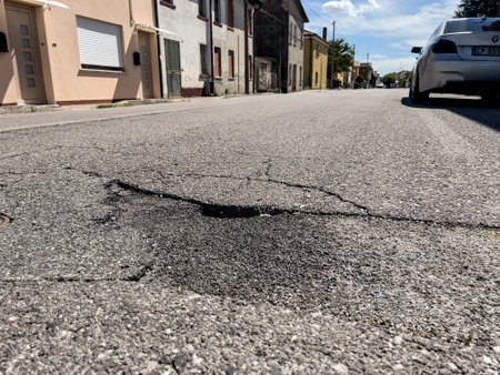 Milan, Italy 29 July 2024: Close-up of a pothole on an urban road in Italy, highlighting poor road maintenance issues.のeditorial素材