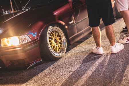 Adria, Italy 30 July 2024: Red BMW E36 with custom spoiler and wheels parked at a gas station at nightのeditorial素材