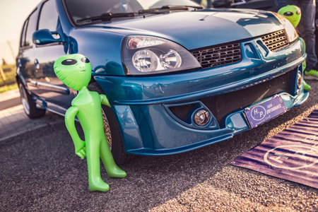 Adria, Italy 30 July 2024: An inflatable alien doll leaning against a blue Renault Clio at a car show.のeditorial素材