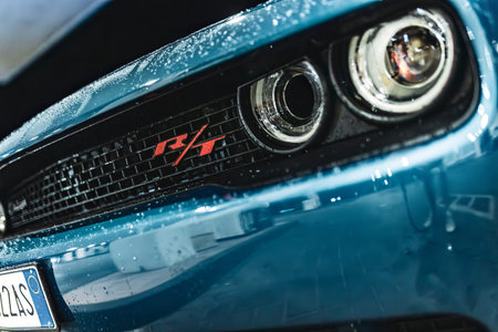 Adria, Italy 30 July 2024: Close-up of the headlight and grille of a blue Dodge Challenger R/T with...