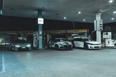 Adria, Italy 30 July 2024: Three different tuned cars parked at a gas station at night, showcasing their unique designs and modificationsのeditorial素材
