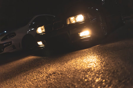 Adria, Italy 30 July 2024: BMW E36 with headlights on, illuminating the road at night, highlighting the car's front design in low lightのeditorial素材