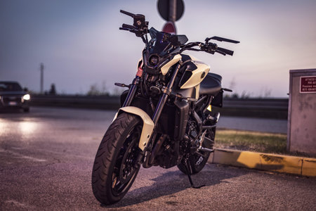 Adria, Italy 30 July 2024: A sleek motorcycle parked by the roadside at sunset, showcasing its...