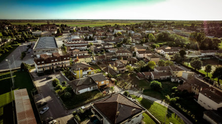 A scenic aerial view of a small town surrounded by greenery, with houses and buildings captured under sunlight. Po valley, Italyの写真素材