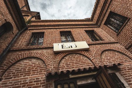 A worn theater sign on an old brick wall, framed by two barred windows above an arched entrance.の写真素材