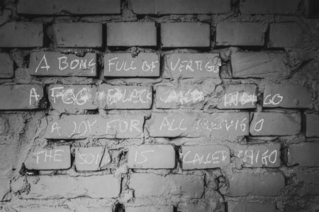 Chalk graffiti scrawled on a worn brick wall, creating an urban art texture in black and white tones.の写真素材