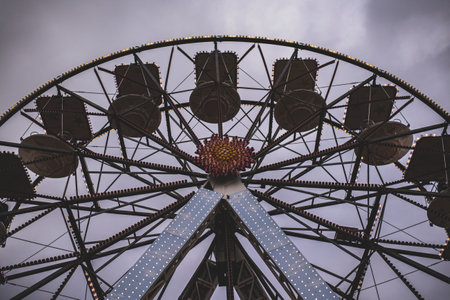 Ferris wheel with empty gondolas standing still under a cloudy sky, waiting for passengersの写真素材
