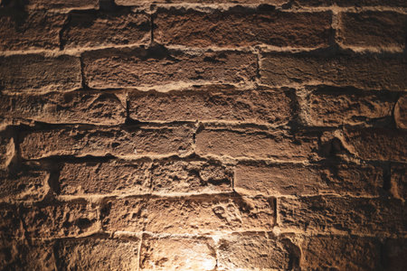 Warm light projecting onto a grunge brick wall creates dramatic shadows, enhancing the visual appeal and texture, making it ideal for backgrounds and artistic designsの写真素材