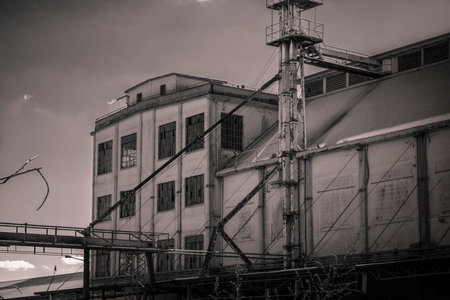 Desolate industrial building with broken windows and rusty pipes, evoking a sense of abandonment and decayの写真素材