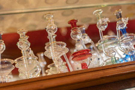 Colorful glass souvenirs are displayed on a wooden shelf in a marsa alam shop, showcasing intricate...