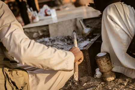 Close-up of a traditional coffee brewing scene in the Marsa Alam desert, showing hands preparing...