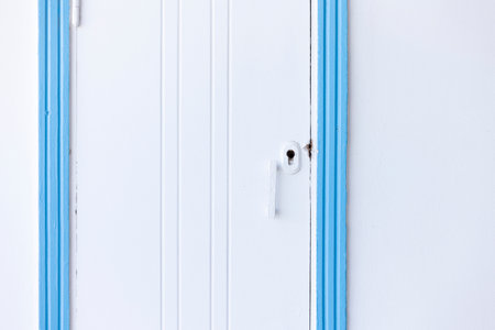 Close-up of a white wooden door featuring a light blue frame and a simple white handle, captured in Marsa Alam, Egyptの写真素材