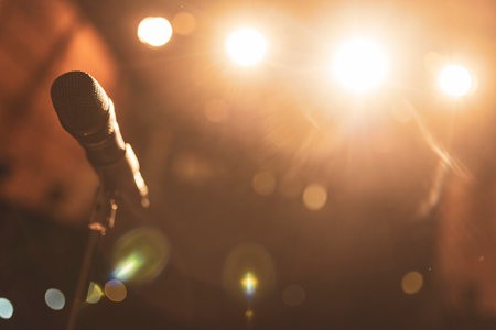 Professional microphone is waiting for the singer on stage under the warm lights, ready for a live performanceの写真素材