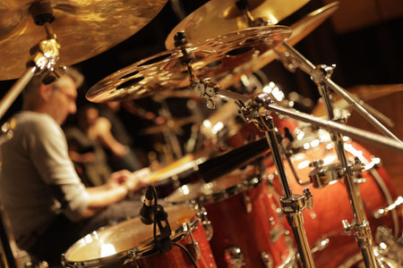 Close up of red drum kit with cymbal and professional drummer playing during rehearsal in recording studioの写真素材