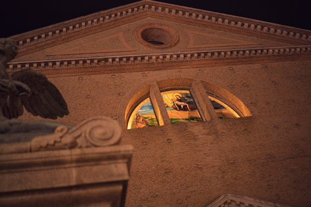 stained glass window depicting a biblical scene illuminates Duomo di Chioggia's facade at night, Chioggia, Italyの写真素材