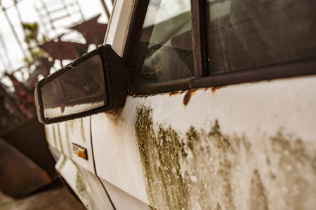 Close up of a rusty, decaying car in a junkyard, highlighting its neglected state and the passage of...