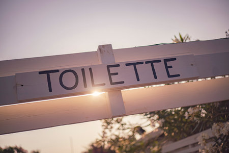 wooden toilet sign with sun shining through at sunset in chioggia, italyの写真素材