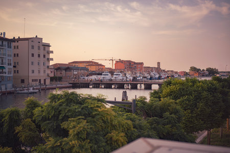 Chioggia, Italy 21 June 2025, scenic view of Chioggia and Sottomarina's canal with moored boats and buildings at sunset, Veneto, Italyの写真素材