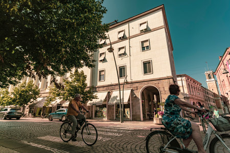 Rovigo, Italy 21 June 2025, two senior citizens cycling on a paved street in Rovigo, Italy, highlight sustainable transportation and an active lifestyleの写真素材