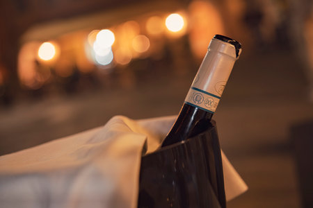 Chioggia, italy 21 June 2025, wine bottle in a wine cooler with a white napkin on a table at a restaurant in chioggia, italy, at nightの写真素材