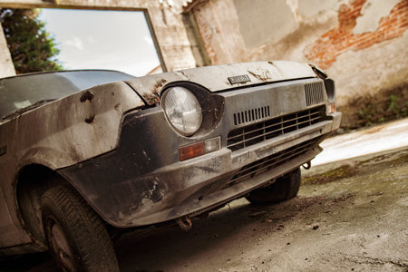Milan, Italy 21 June 2025, rusty abandoned fiat 127 car parked near a damaged building, showing decay and neglectの写真素材