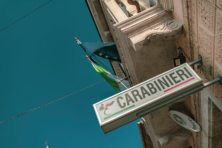 Rovigo, Italy 21 June 2025, low angle view of a carabinieri station sign with Italian and European Union flags waving against a clear blue sky in Rovigo, Italyの写真素材