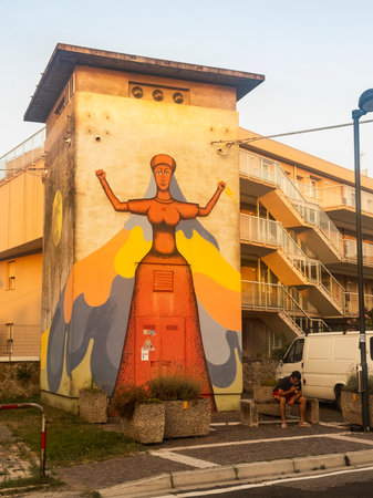 Rosolina Mare, Italy 21 June 2025, street art featuring a woman holding fire and water, representing balance and power, adorns an electrical cabin in a residential areaの写真素材