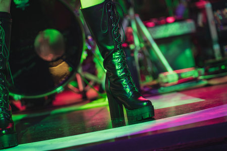 High heeled black boots with laces showcased on a colorful stage, capturing the essence of live performance and dynamic lightingの写真素材