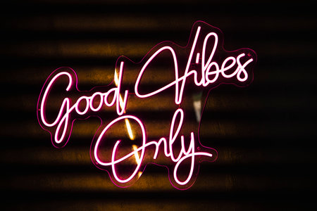 Vibrant pink neon sign displaying the words good vibes only against a dark background, creating a lively and optimistic atmosphereの写真素材