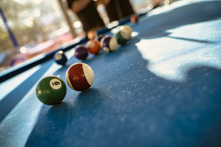 Colorful billiard balls lie on a blue pool table, suggesting a game in progress, with the focus on...