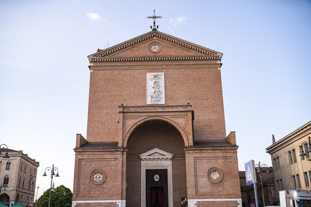 Neoclassical facade of the duomo of cavarzere rising above the square, featuring a large arch, brick...