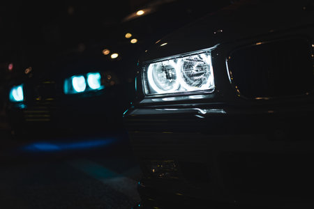 Car headlights cutting through the darkness of a night road, casting a dramatic glow and enhancing the atmospheric sceneの写真素材