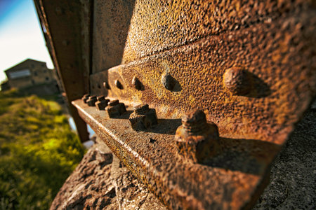 Close-up of rusty bolts and rivets on a weathered metal beam, highlighting the decay and age of an...