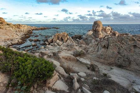Granite rock formations rising from the turquoise waters of the Mediterranean sea at Punta Molentis beach in Villasimius, Sardinia, Italy, creating a dramatic coastal landscapeの写真素材